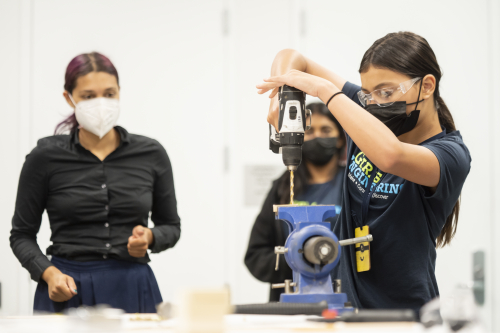 Girls in Engineering student using a drill